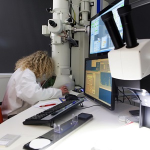 Technicienne de laboratoire analyse un echantillon à microscopie optique à lumière polarisante (MOL)